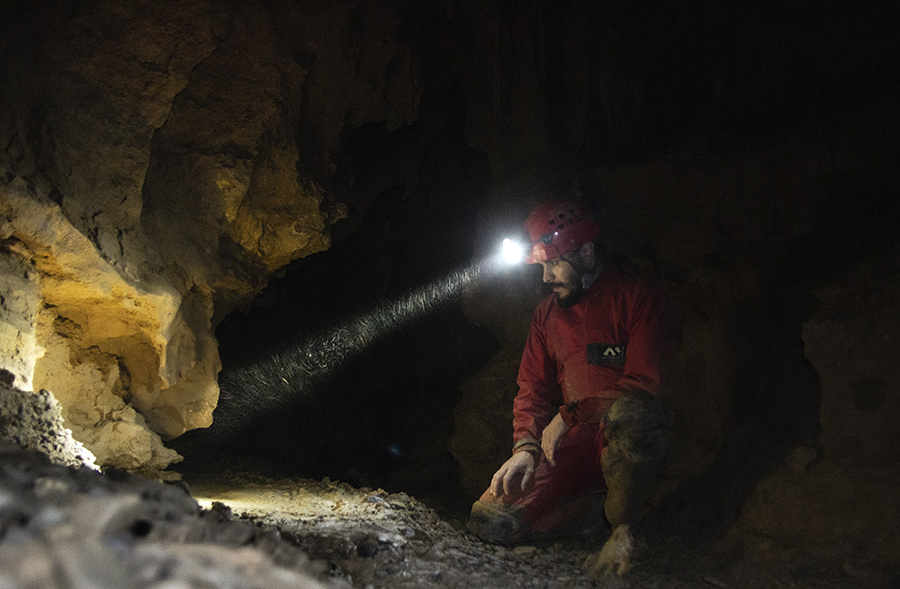 Ionuț Mirea în Peștera Muierilor uităndu-se la fosile de urși de peșteră